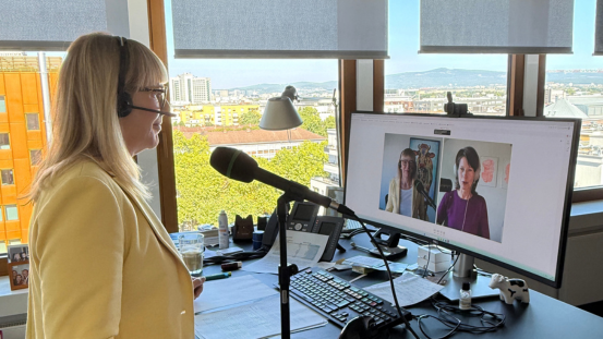 Nikola Steinbock steht an ihrem Schreibtisch und führt ein Onlinemeeting ein Gespräch für den Podcast 