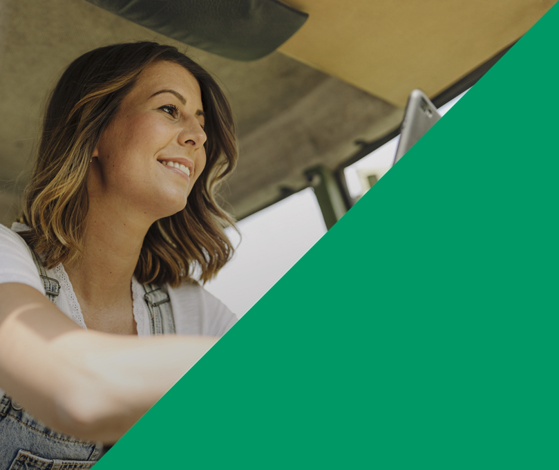 Zweigeteilter Header. Links sitzt eine Frau in einer Traktorkabine und schaut lächelnd auf ihr Smartphone. Rechts eine grüne Fläche. Venture Capital Beteiligungen